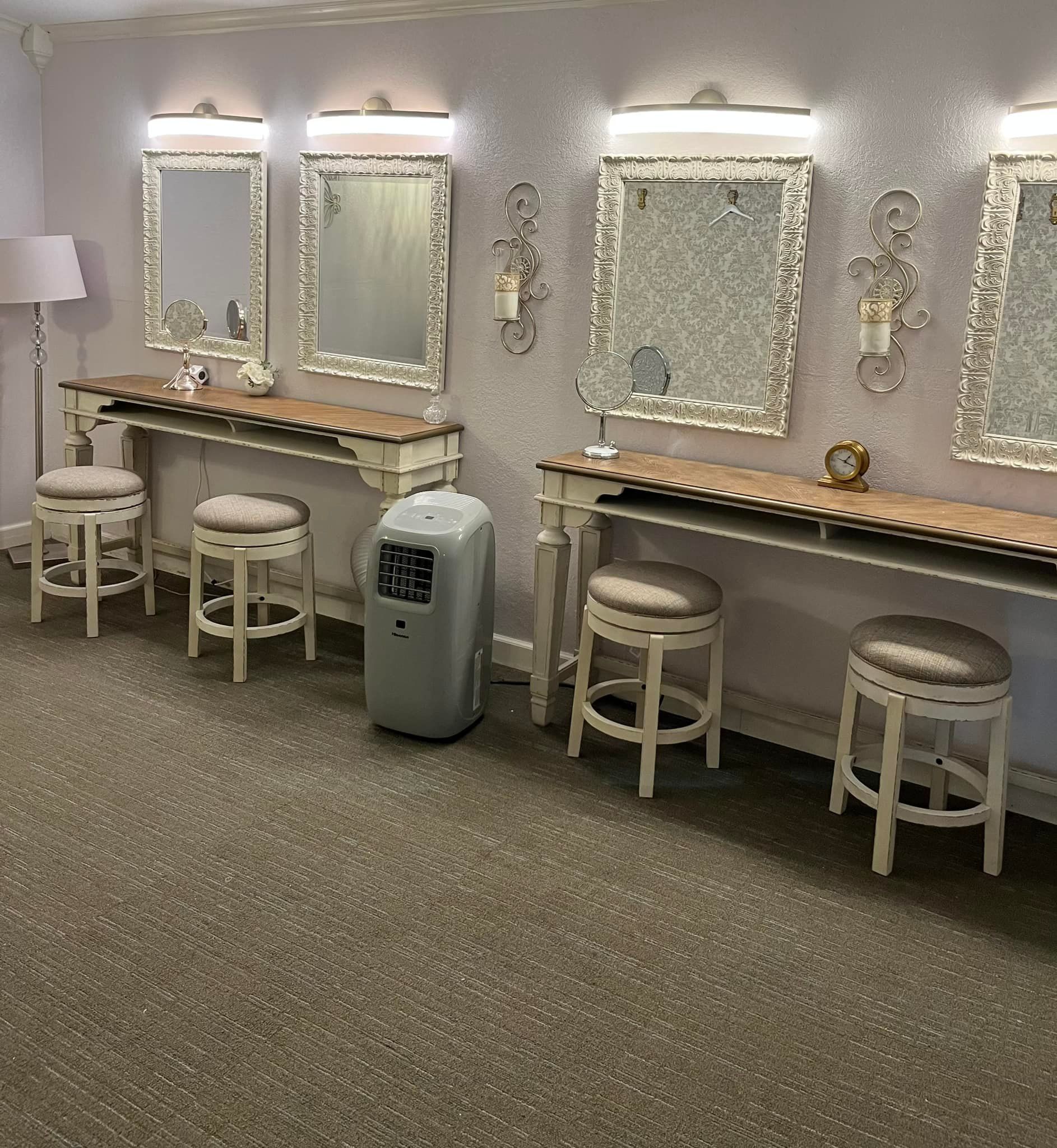 A dressing room with tables , stools and mirrors.