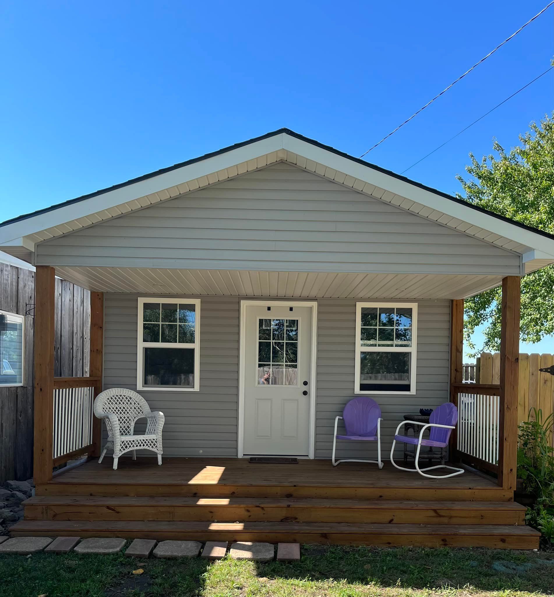 A small house with a porch and chairs on it