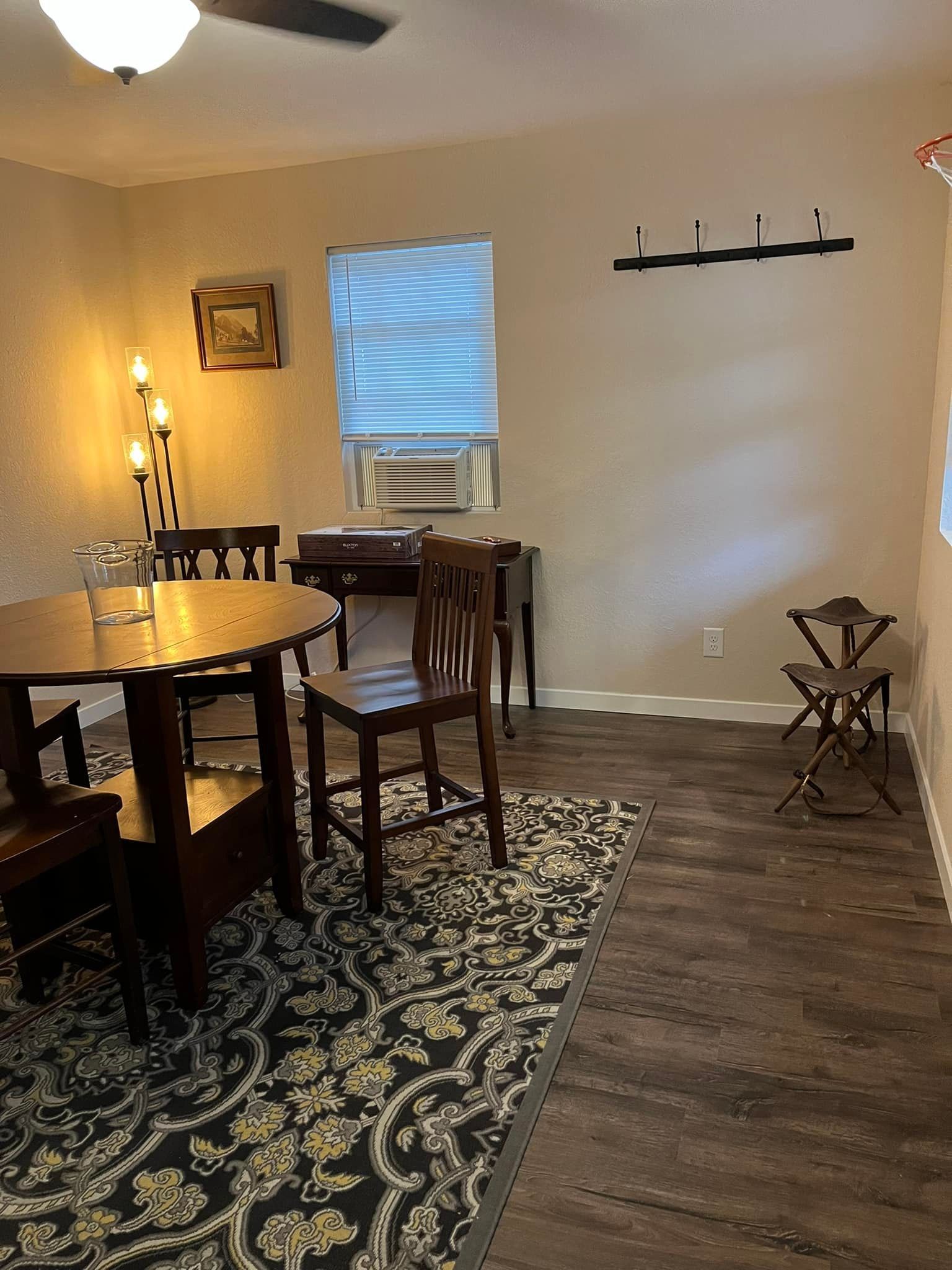 A dining room with a table and chairs and a rug.