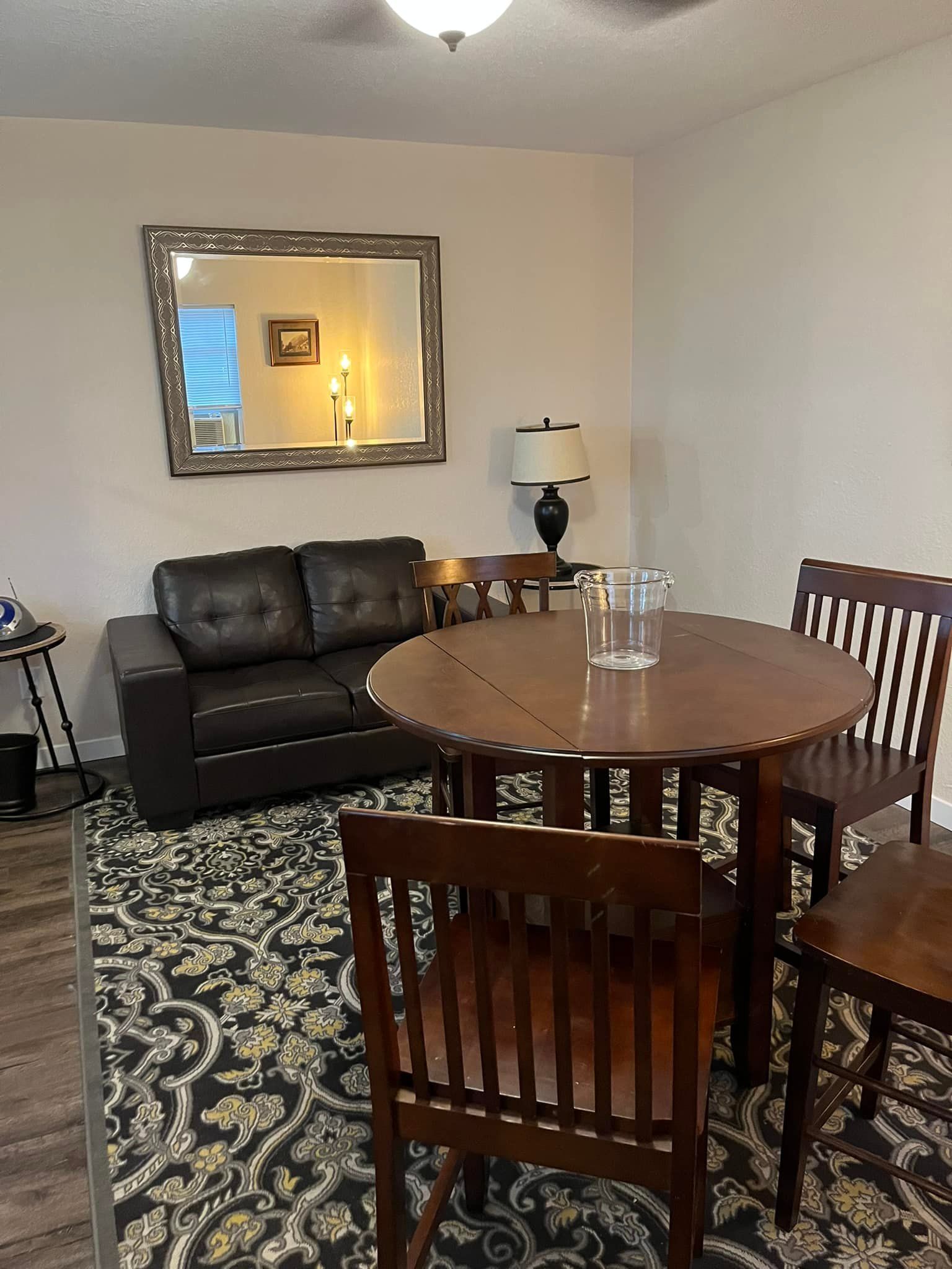 A living room with a couch , table , chairs and a mirror.