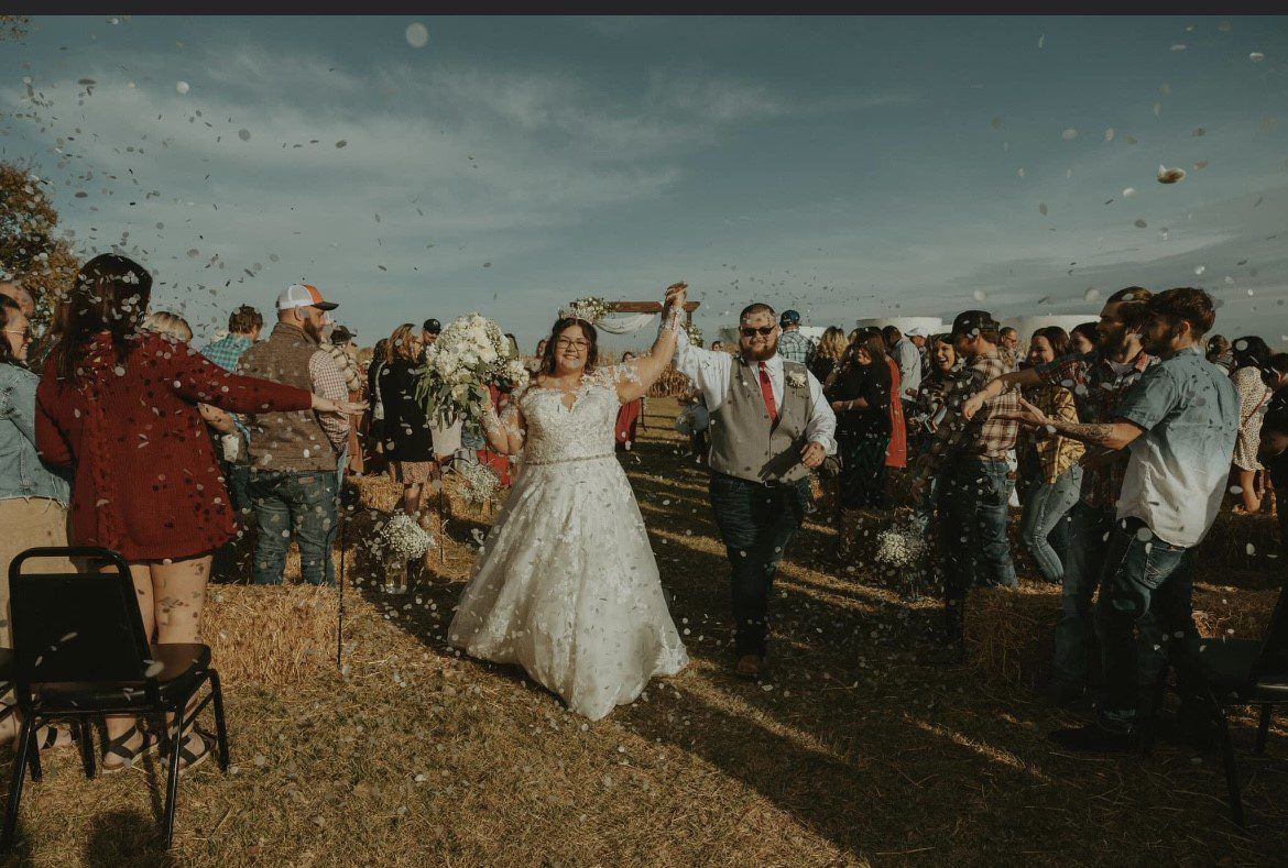 A bride and groom are walking down the aisle surrounded by confetti.