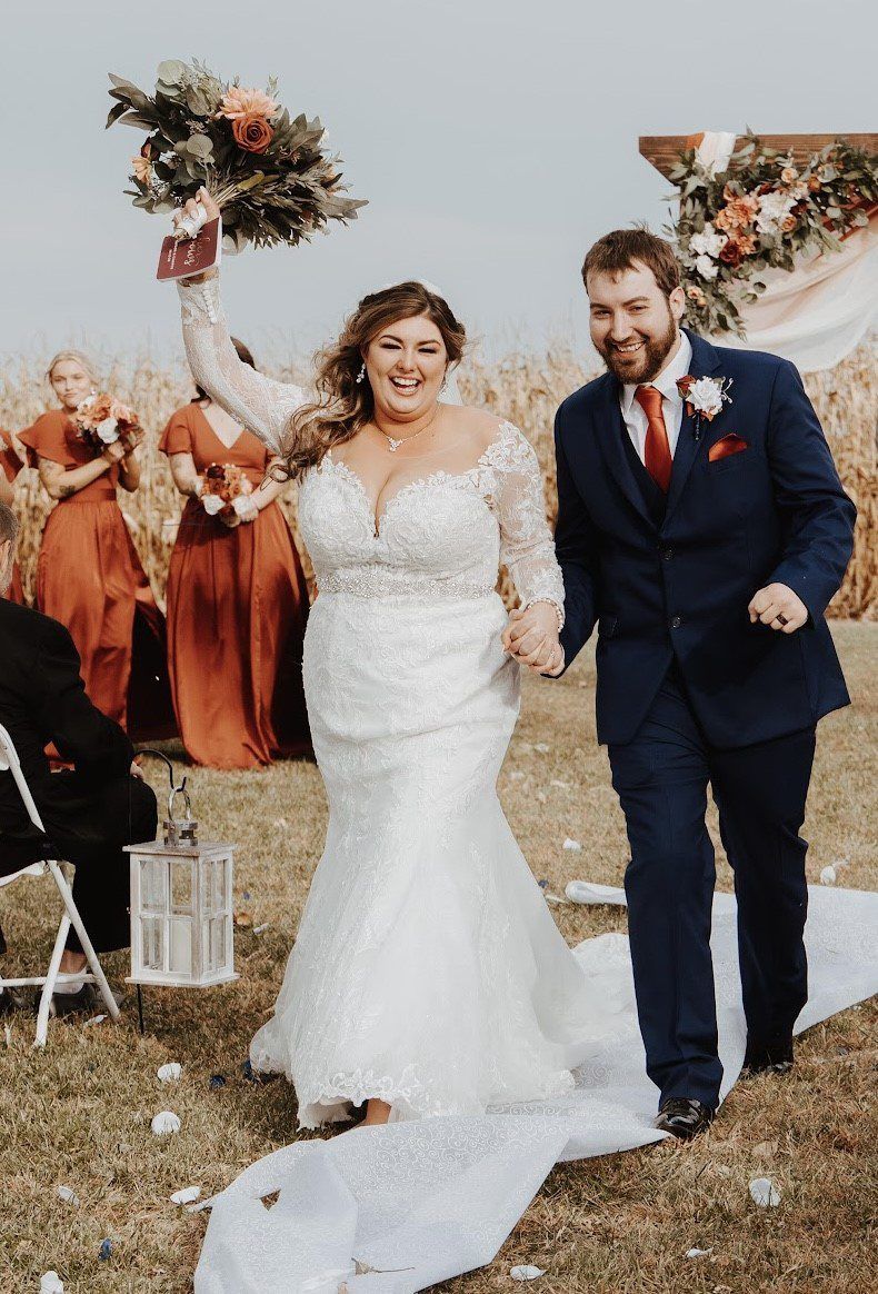 A bride and groom are walking down the aisle at their wedding holding hands.