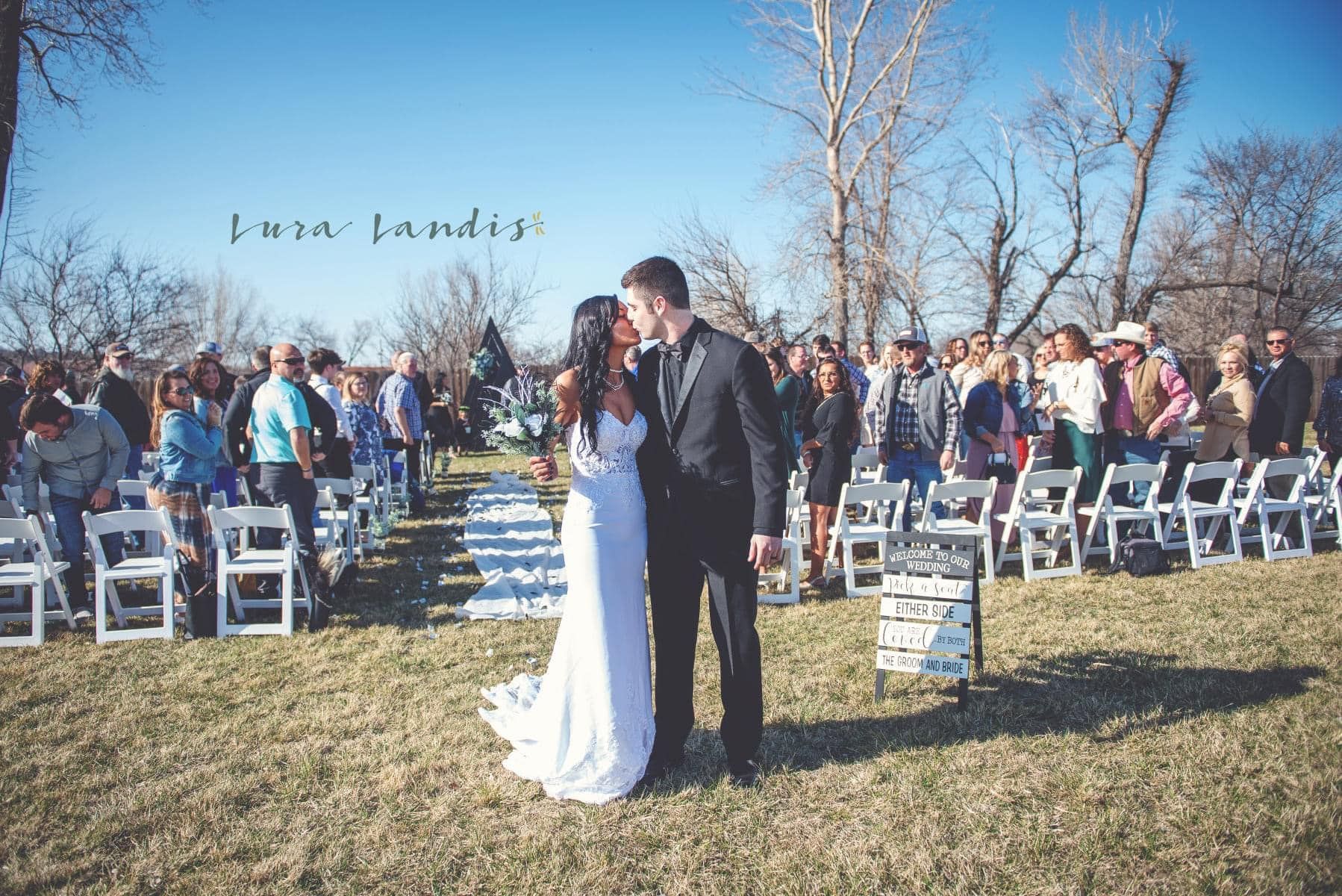 A bride and groom kissing in front of their wedding guests.