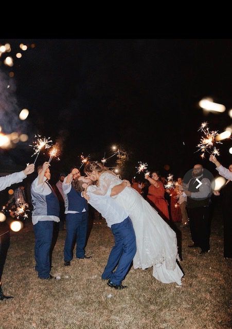 A bride and groom are kissing while holding sparklers.