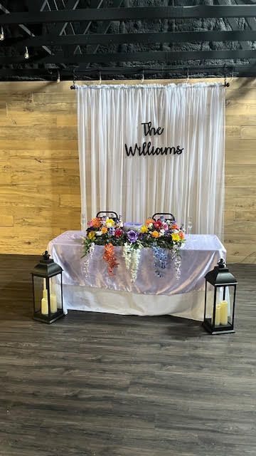 A wedding table with flowers and lanterns in front of a white curtain.