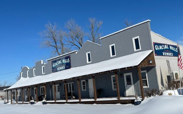 A building with a porch and a sign that says ' glacial falls ' on it is covered in snow.
