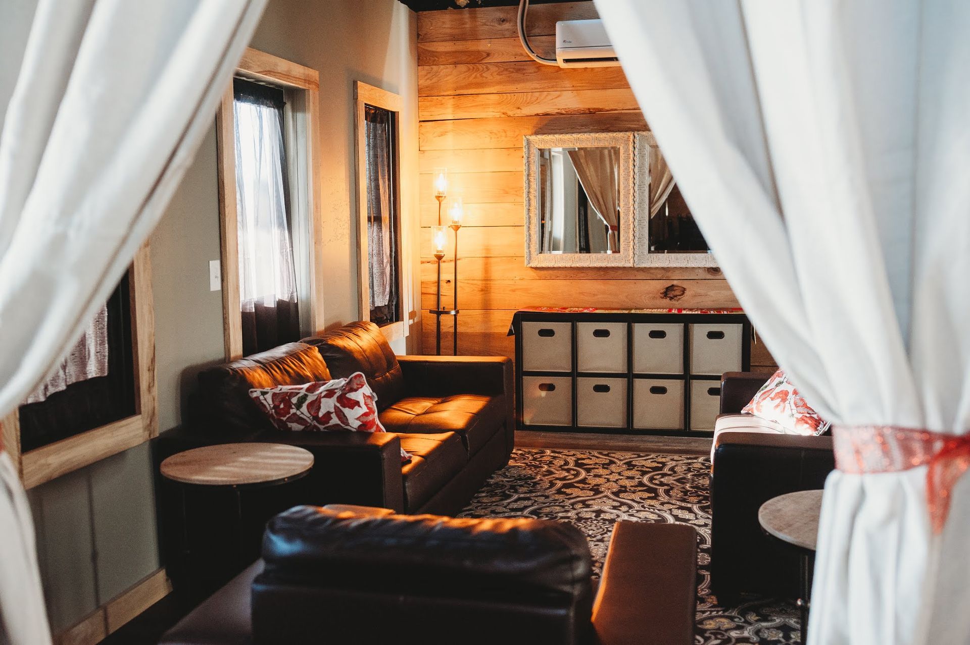 A living room with a couch , chairs , tables and curtains.