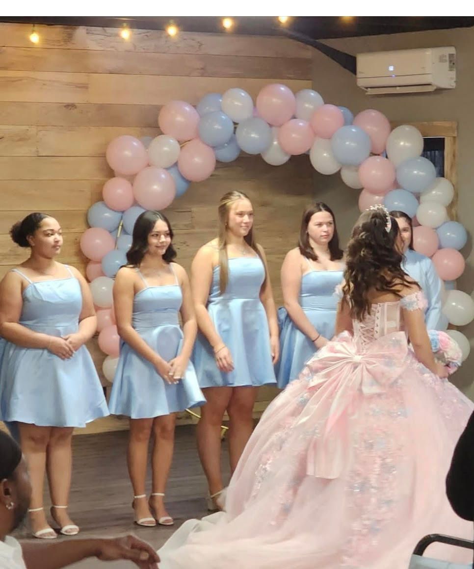 A woman in a pink dress is standing in front of balloons.