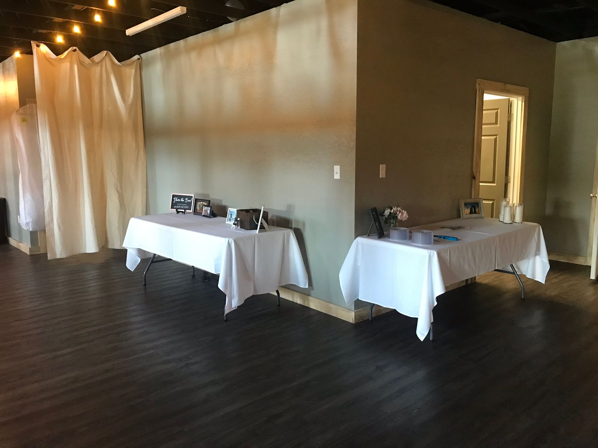 There are two tables in the room with white tables cloths.