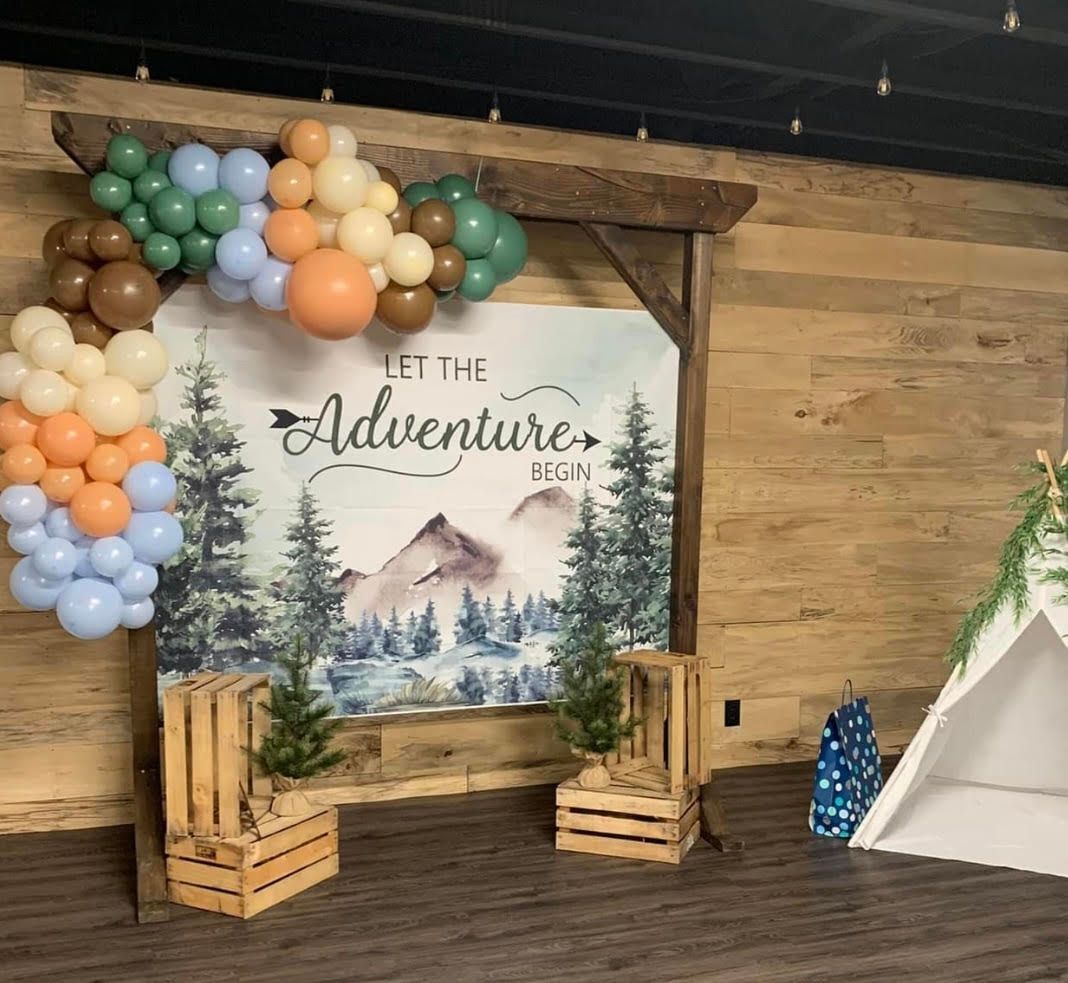 A wooden wall with a sign that says let the adventure begin