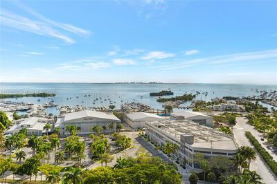 Aerial view of a coastal city with a harbor full of boats under a clear blue sky.