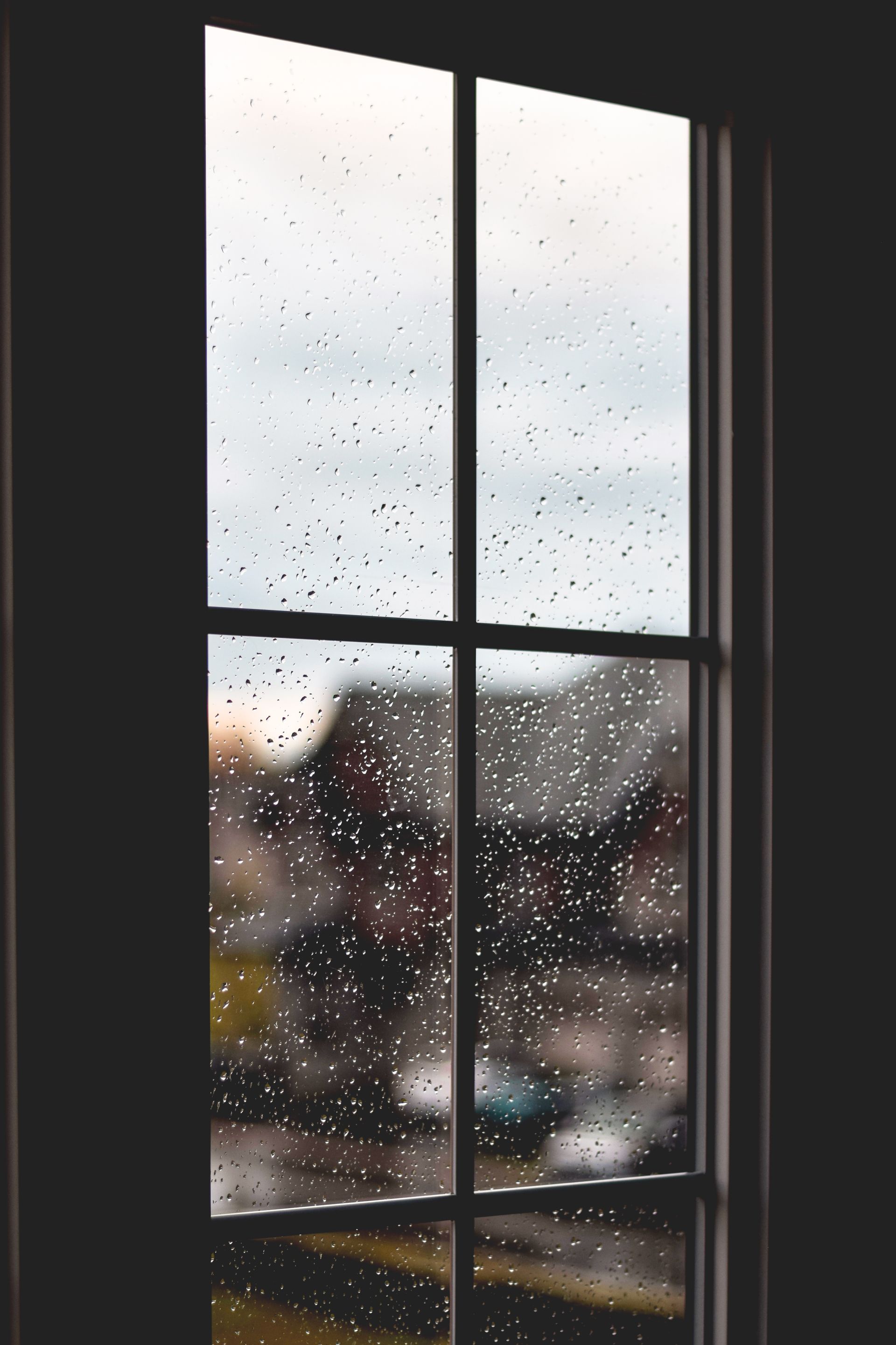 A window with rain drops on it and a view of a city.