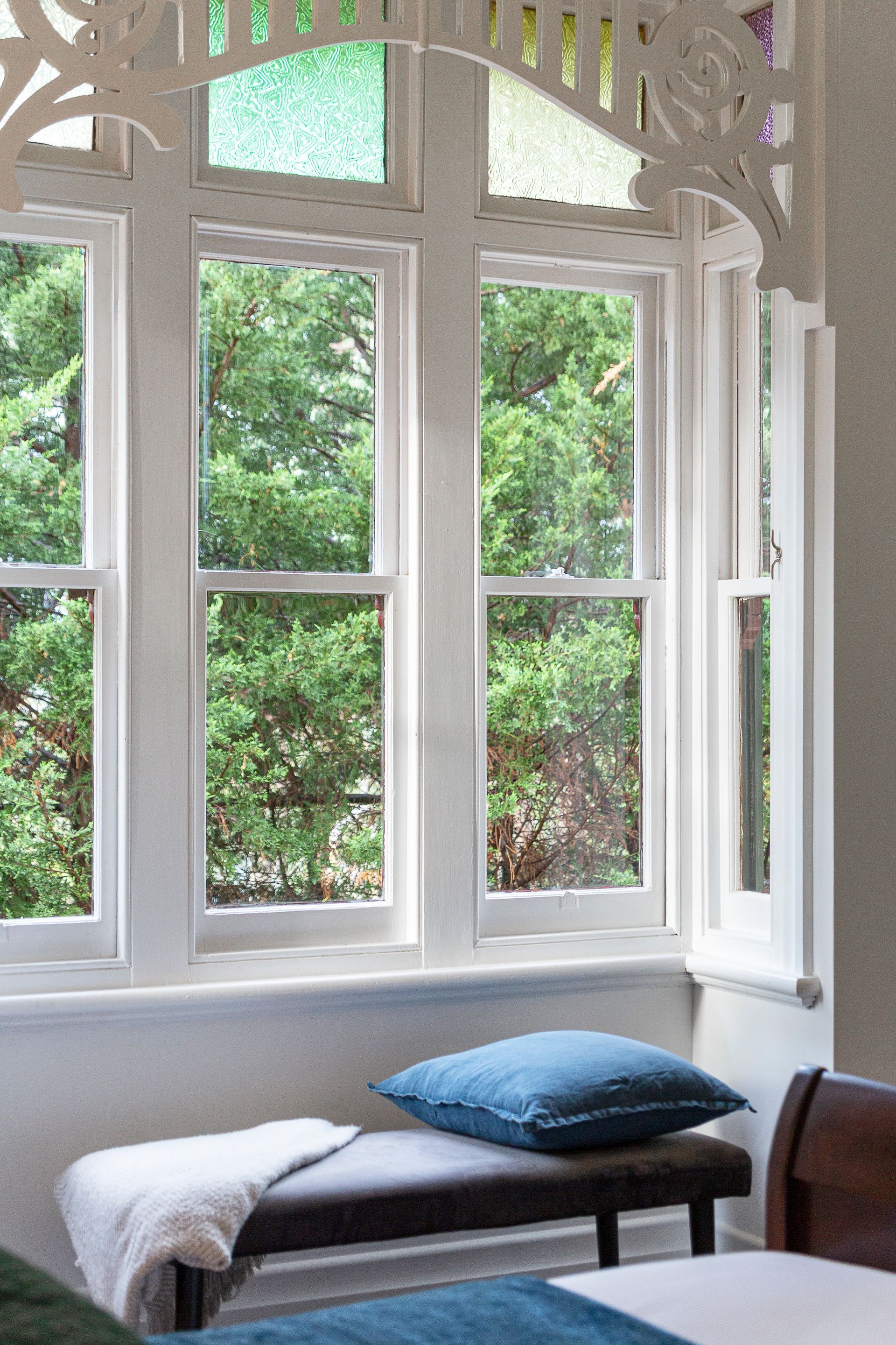 A bedroom with two beds and a bench in front of a window.