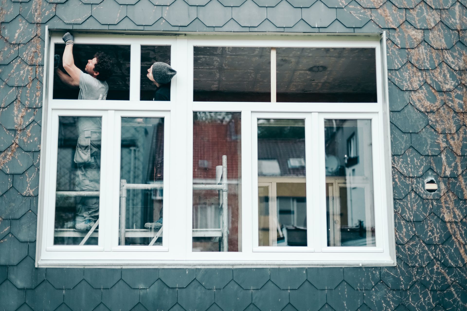 A man is installing a window on the side of a building.