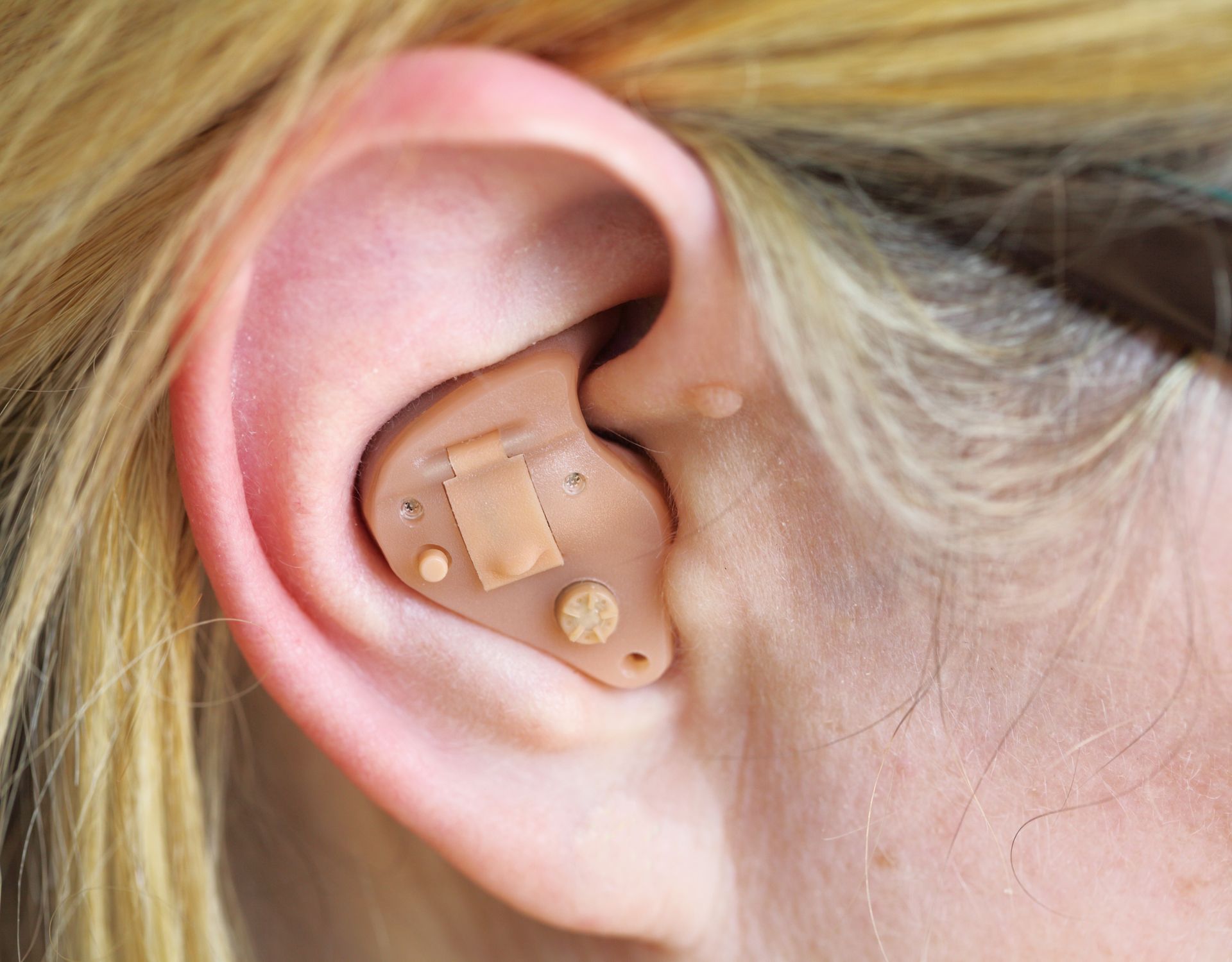 A woman is wearing a hearing aid in her left ear.