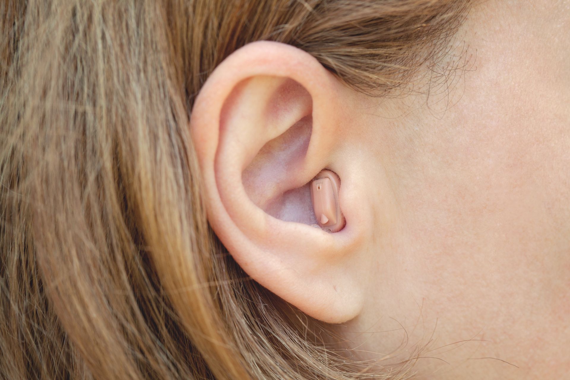A close up of a woman 's ear with a hearing aid in it.