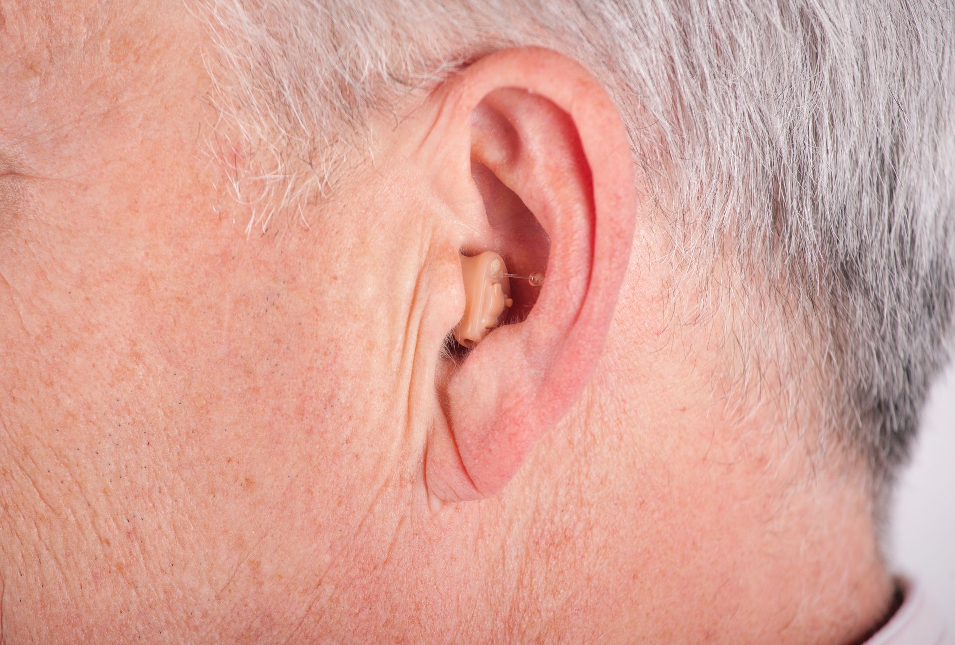 A close up of an elderly man 's ear with a hearing aid in it.