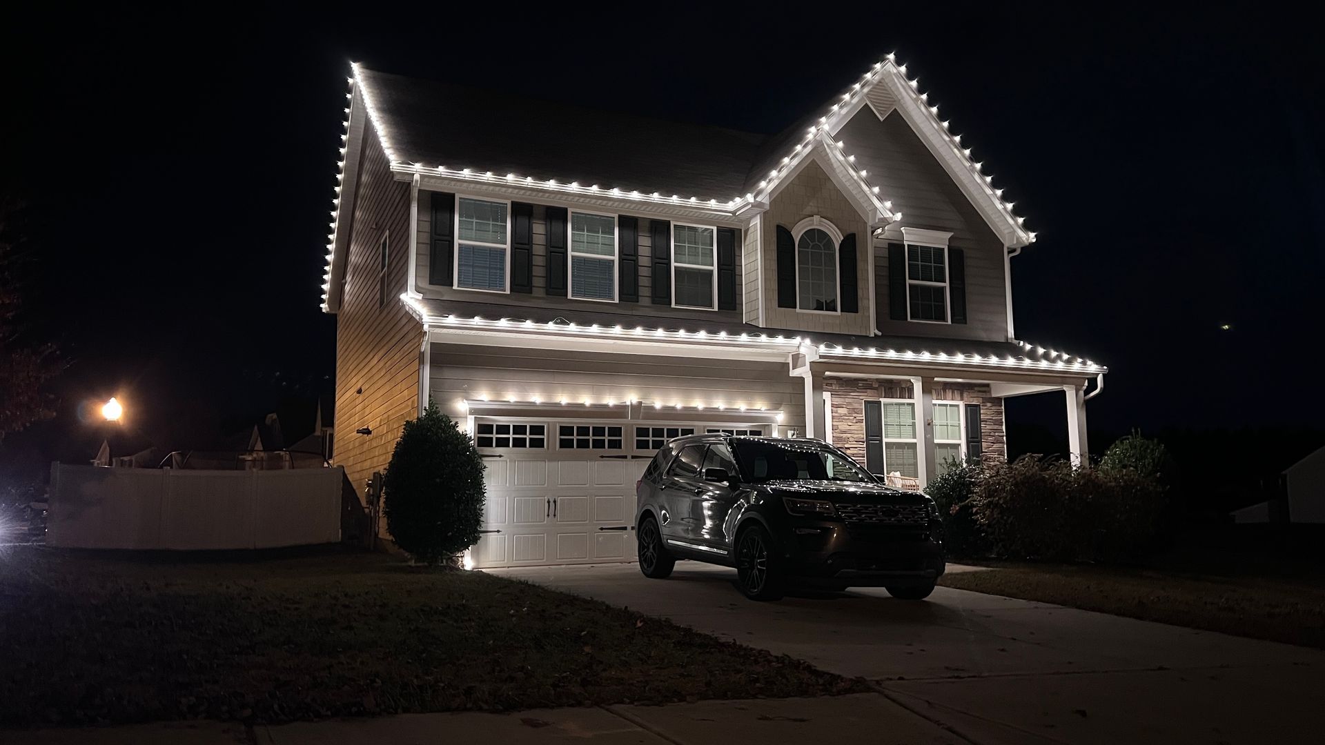 Two-story home with classic Christmas lighting on roofline and porch