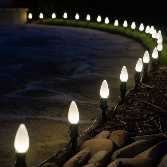 White outdoor lights line a curved stone walkway at night.