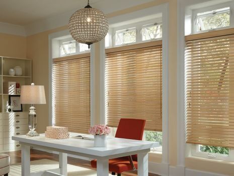 A home office with a desk , chair , lamp and blinds.