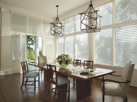 A dining room with a long table and chairs and lots of windows.