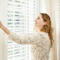 Girl Opening Window Blinds — Los Angeles, CA — Sylvan's & Phillip's Drapes & Blinds