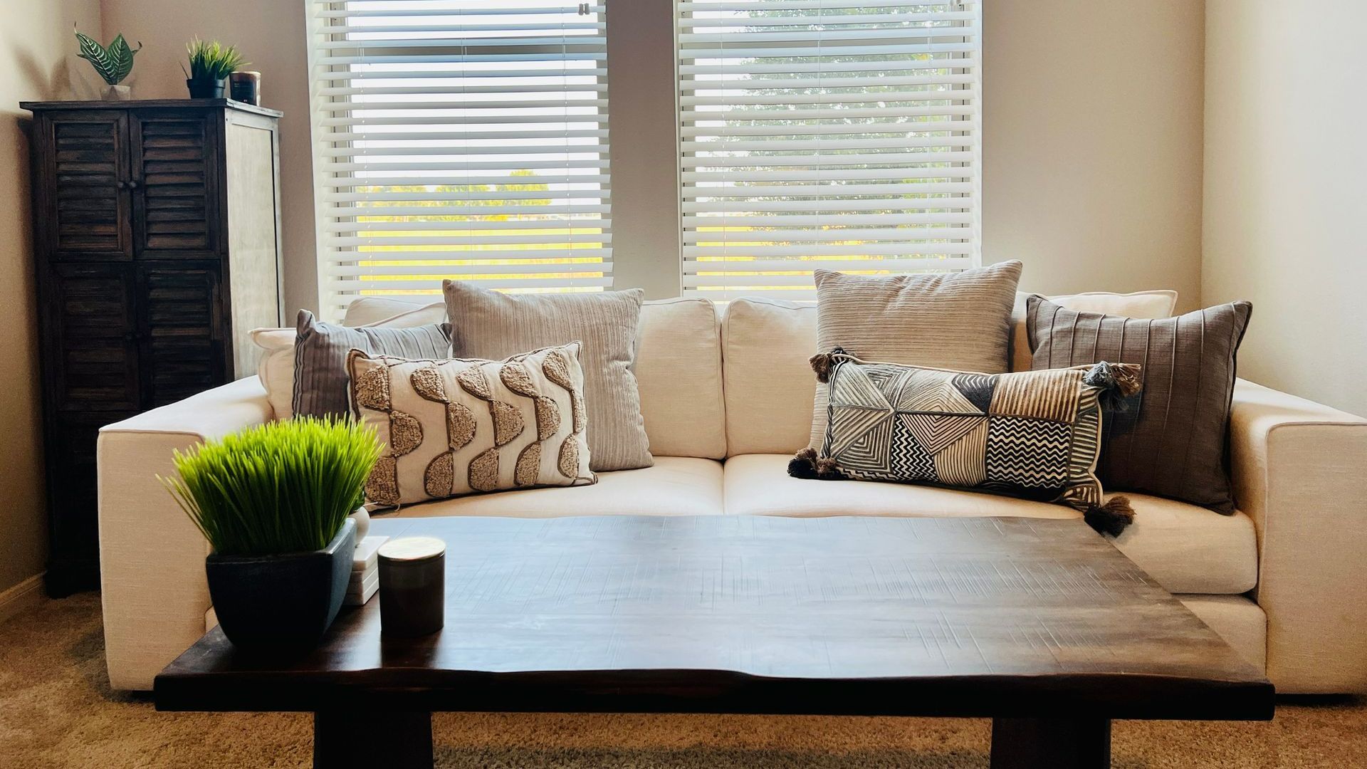 A living room with a couch , coffee table , and two windows.