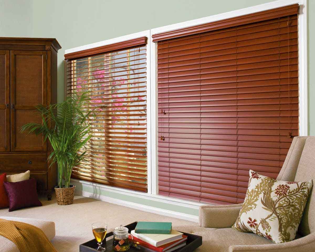 A living room with wooden blinds on the windows and a chair.