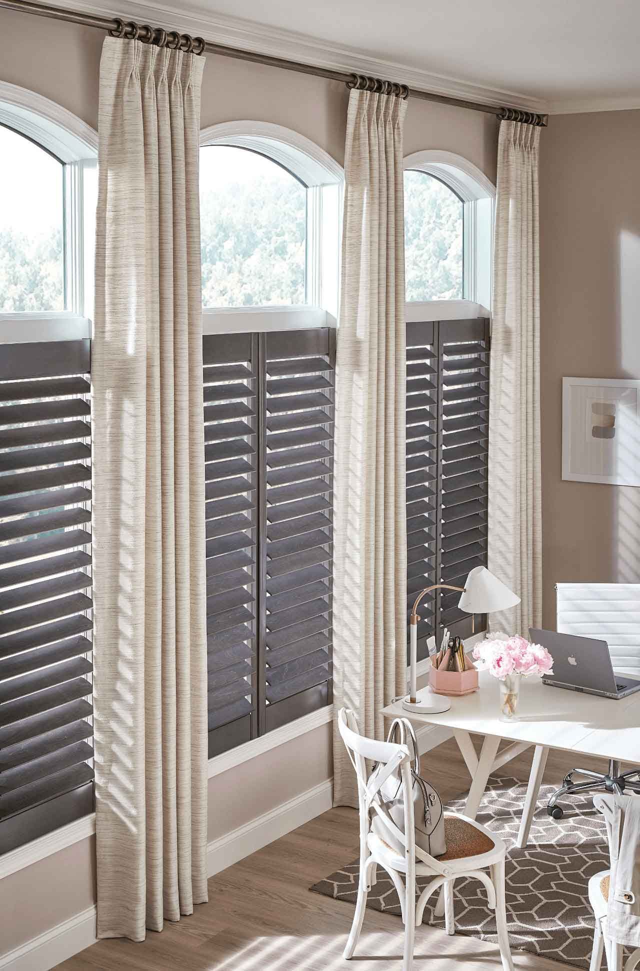 A room with a desk and chairs and shutters on the windows.