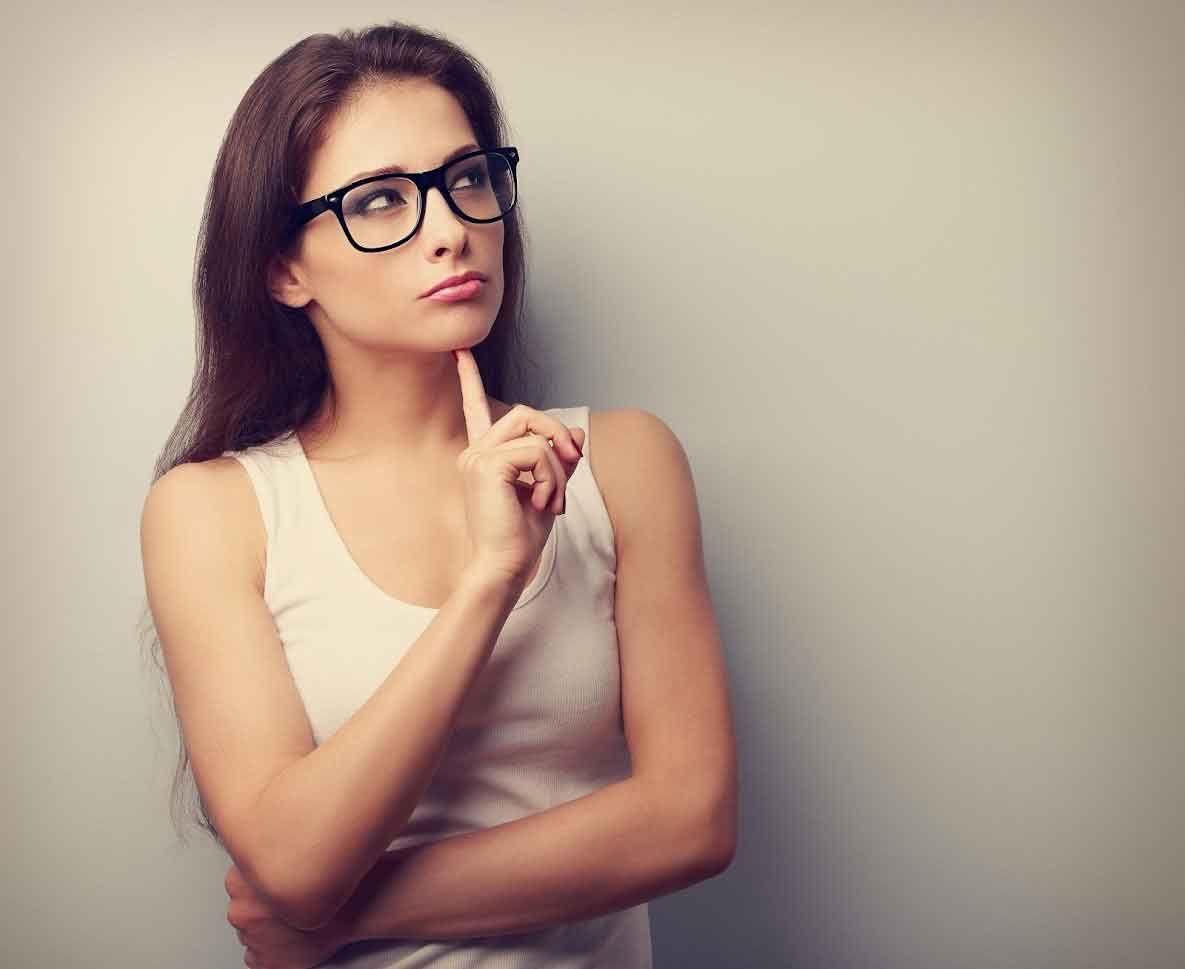 A woman wearing glasses and a white tank top is thinking.