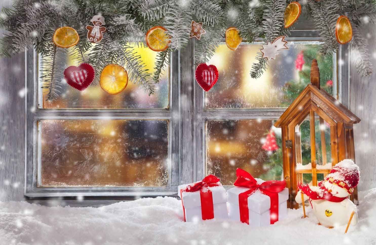 A window with christmas decorations on it and a christmas tree in the background.