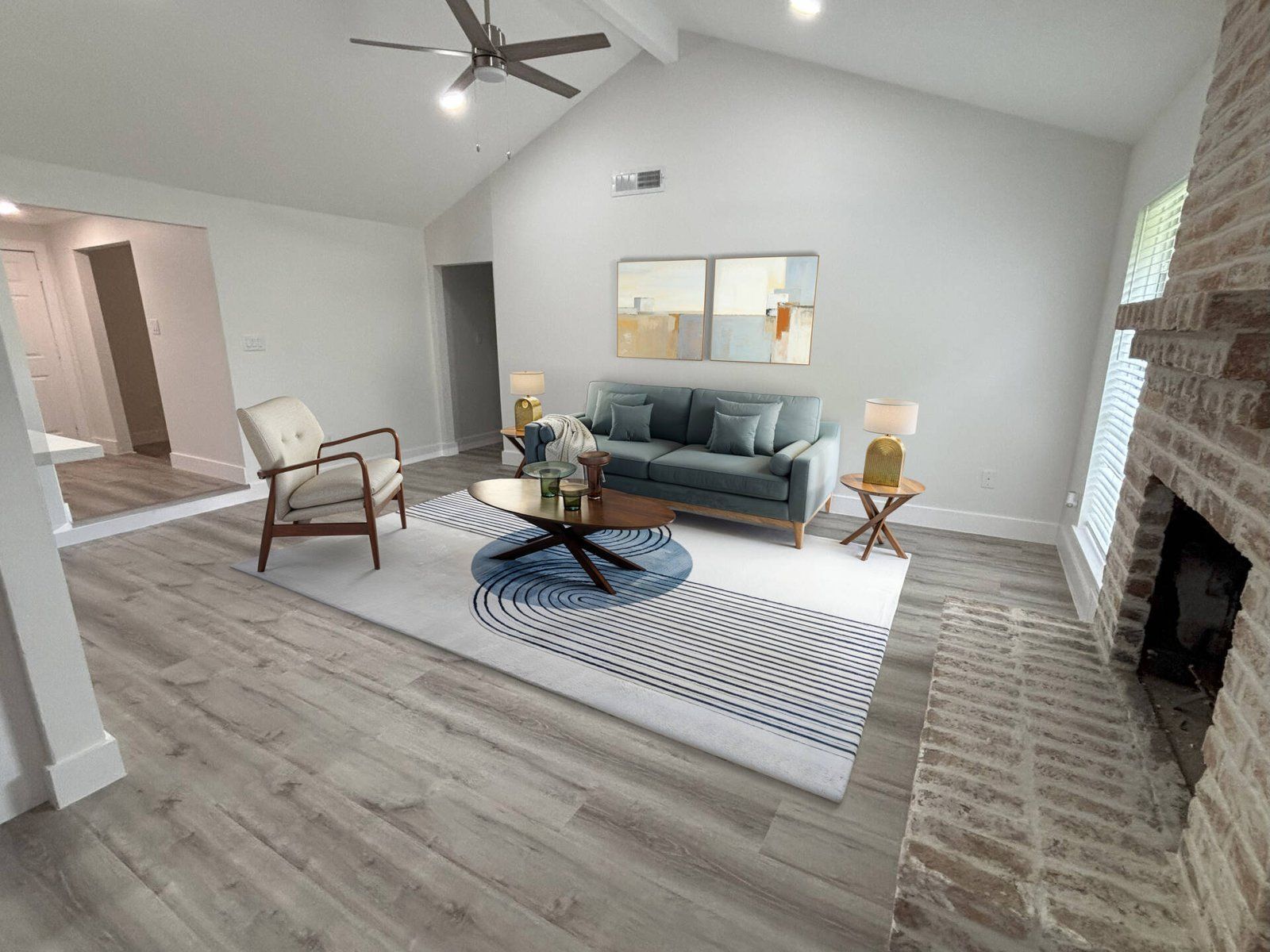 Living room with blue sofa, brick fireplace, gray floors, and patterned rug.