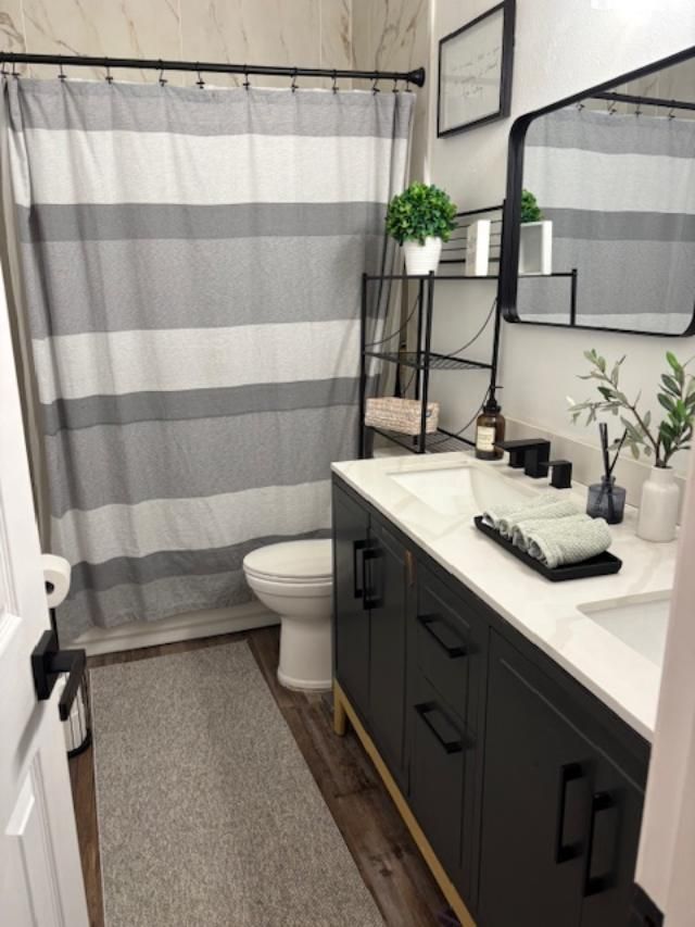 Modern bathroom with gray vanity, striped shower curtain, and decorative accents.