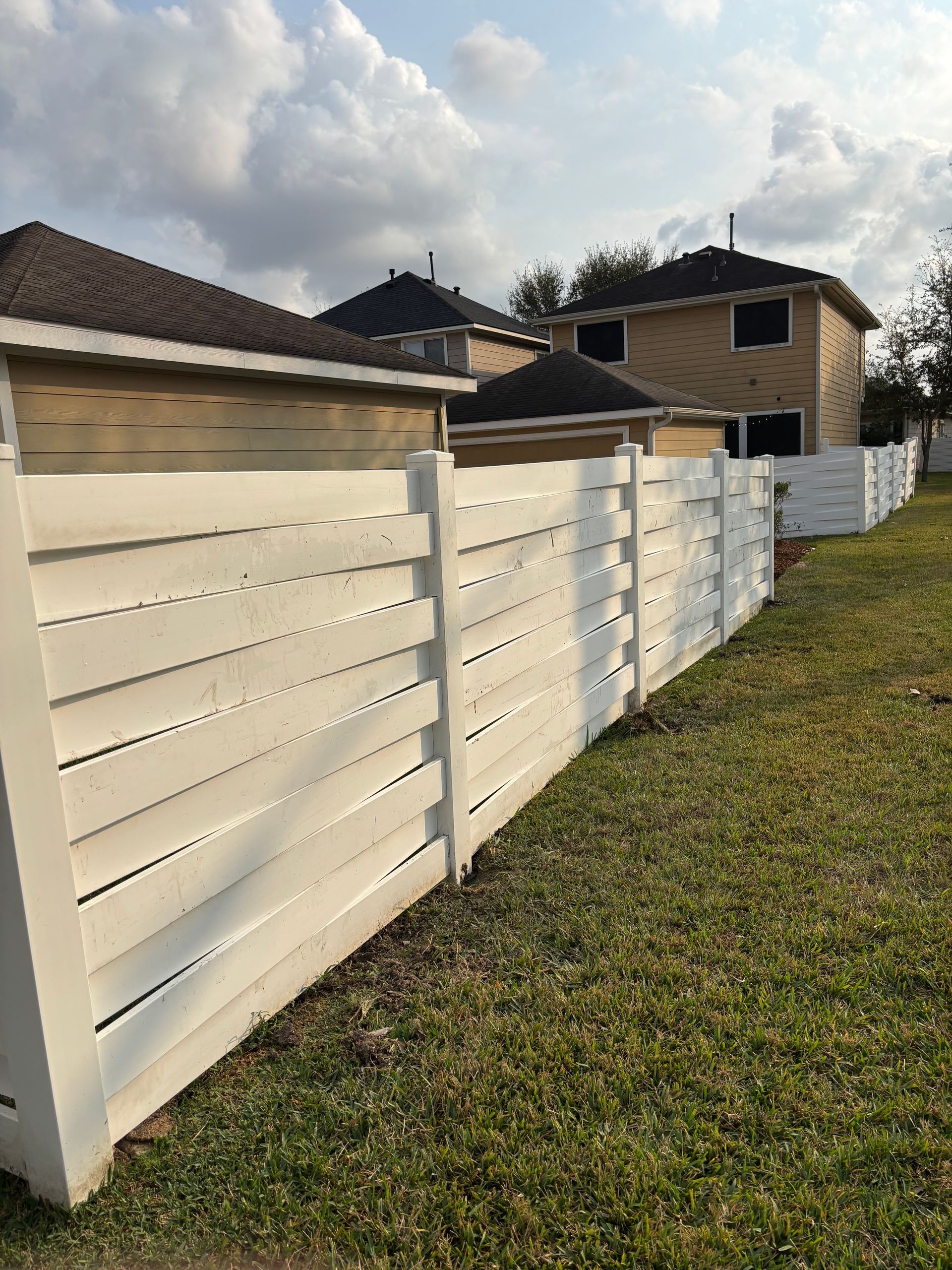 White kitchen with stainless steel refrigerator, white cabinets, dark wood floor, and window.