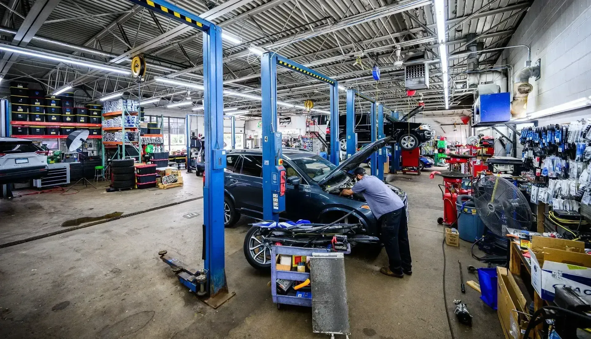 Mechanic working on a car in a well-lit auto repair shop with multiple lifts | Autopia Auto Repair - Bloomington