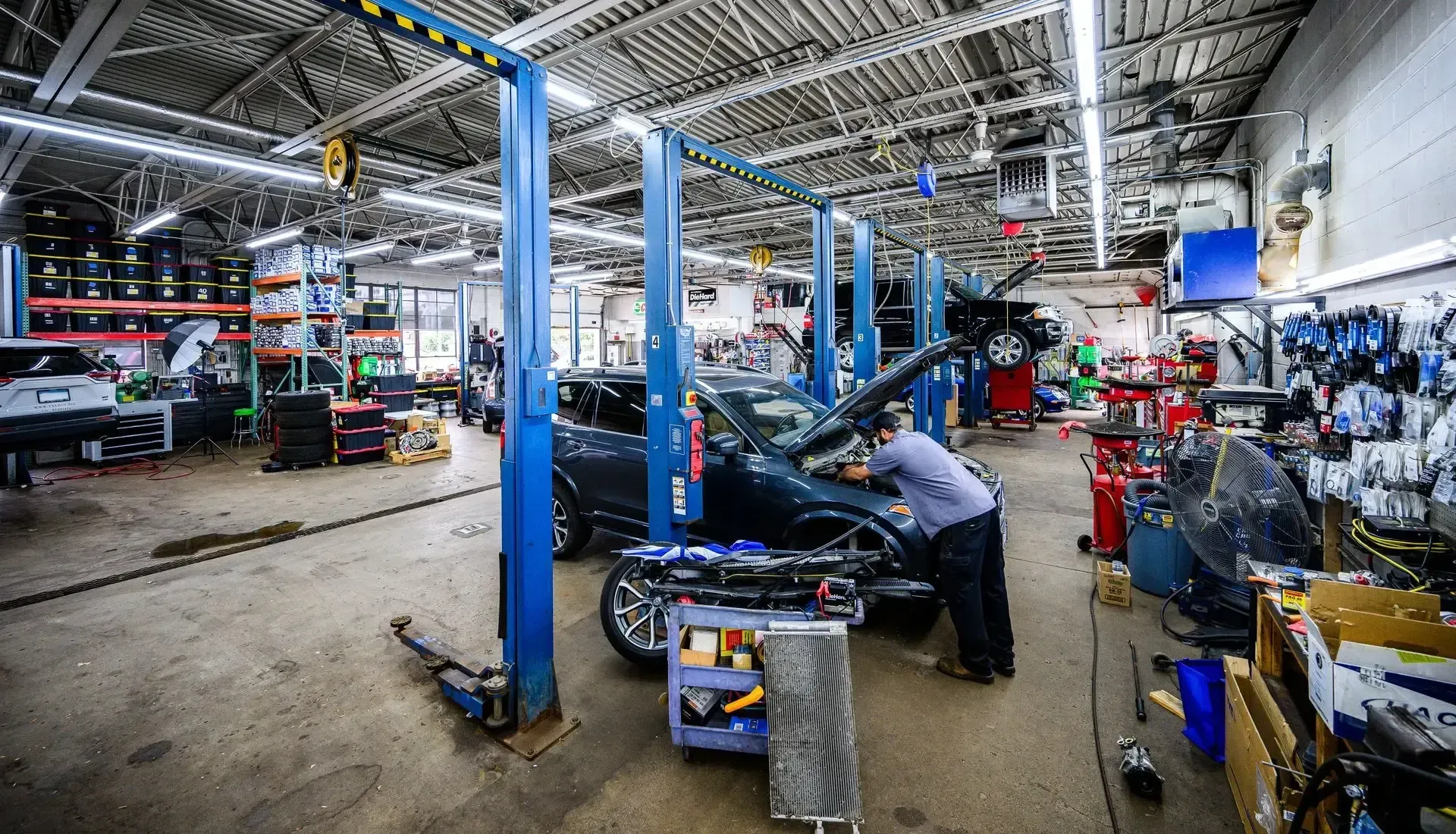 Mechanic working on a car in a well-lit auto repair shop with multiple lifts | Autopia Auto Repair - Bloomington