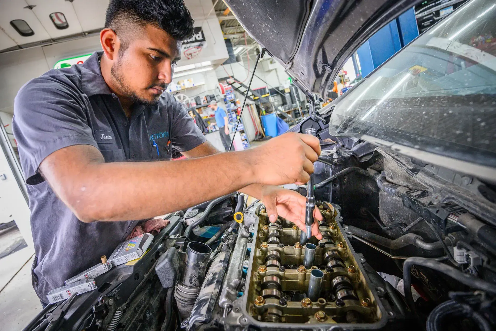 Mechanic working on a car engine with a wrench in a garage | Autopia Auto Repair - Bloomington