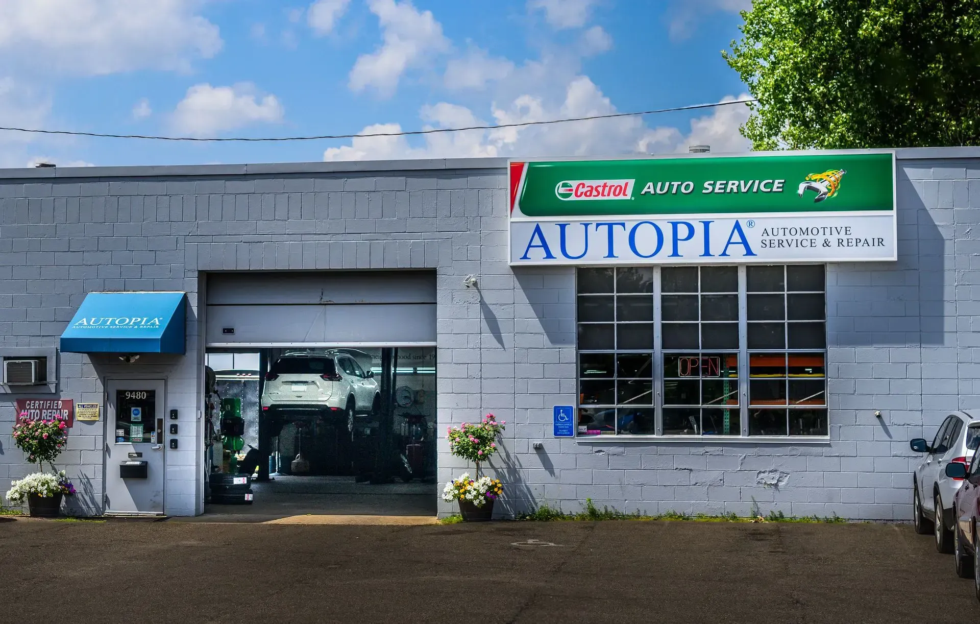 Grey auto repair shop with open garage door; sign reads “Autopia Auto Service” | Autopia Auto Repair - Bloomington