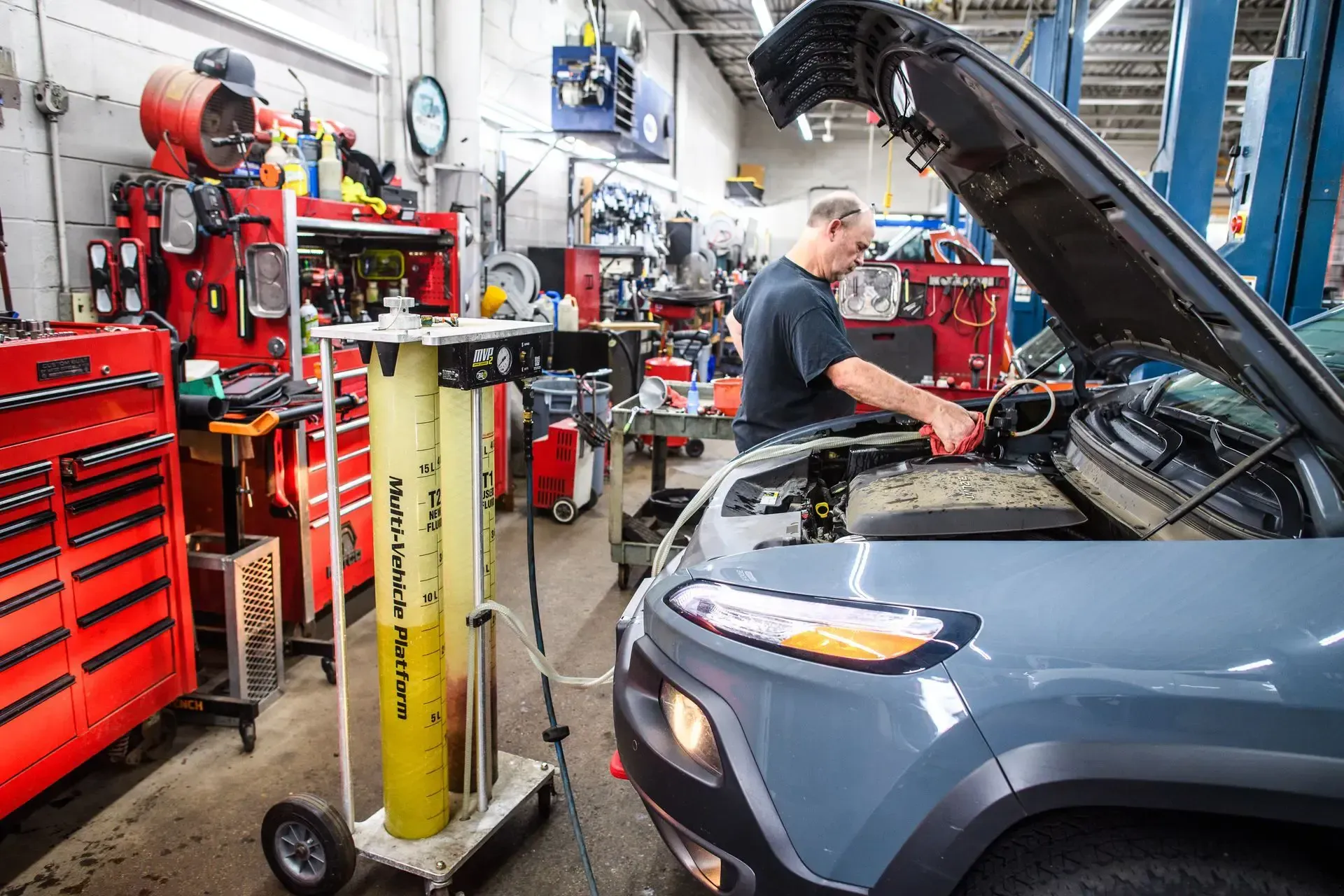 Mechanic working on a car in a repair shop. Open hood, tools, and equipment are visible | Autopia Auto Repair - Bloomington