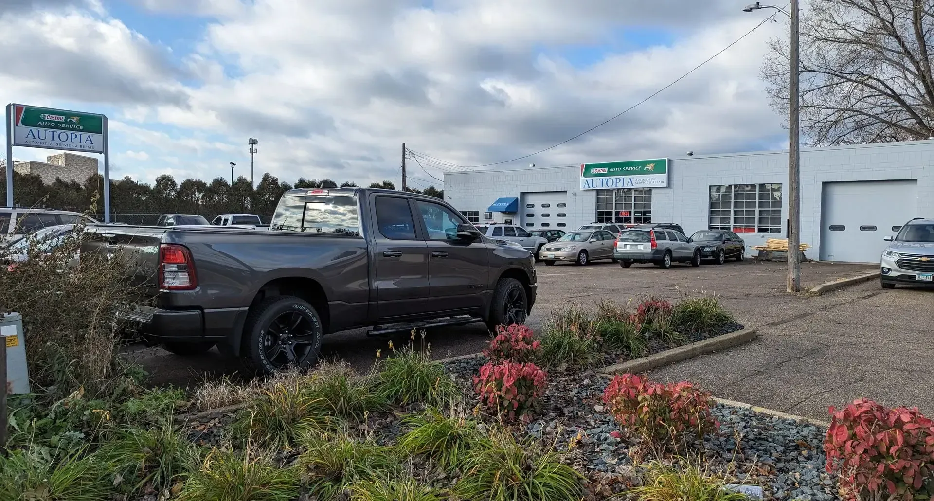 Dark gray pickup truck parked near a car dealership on a cloudy day | Autopia Auto Repair - Bloomington