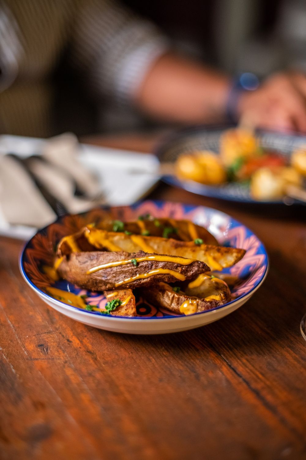 A close up of a plate of french fries on a wooden table.