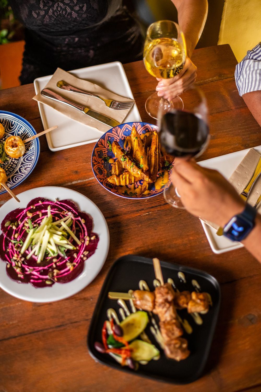 A table topped with plates of food and glasses of wine.