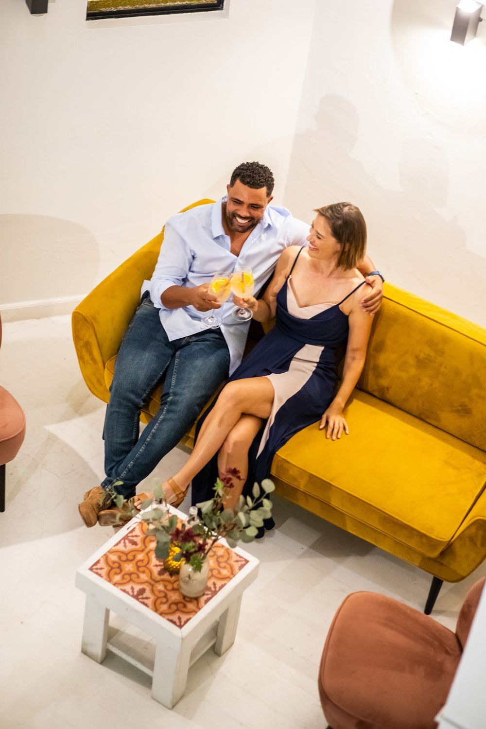 A man and a woman are sitting on a yellow couch.