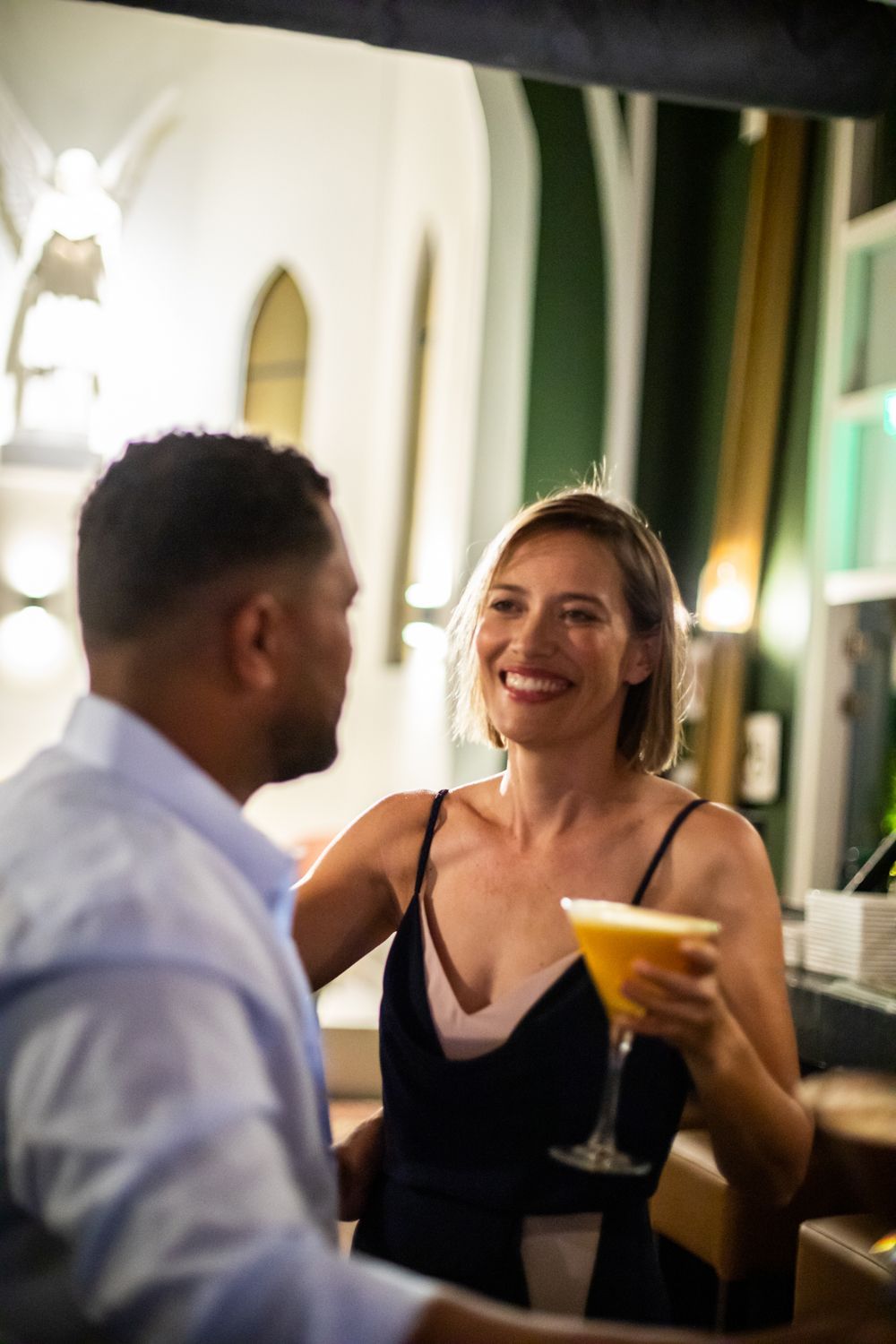 A man and a woman are sitting at a bar drinking cocktails.