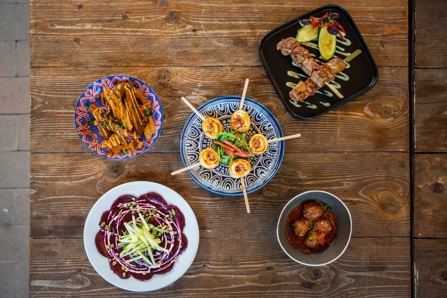 A wooden table topped with plates of food and bowls of food.