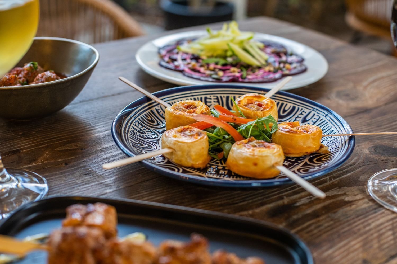 A wooden table topped with plates of food and a glass of beer.