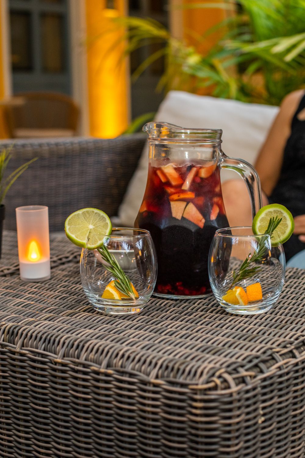 A pitcher of wine and two glasses of wine are on a table.