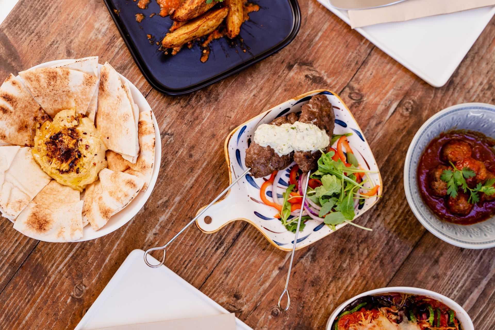 A wooden table topped with plates and bowls of food.