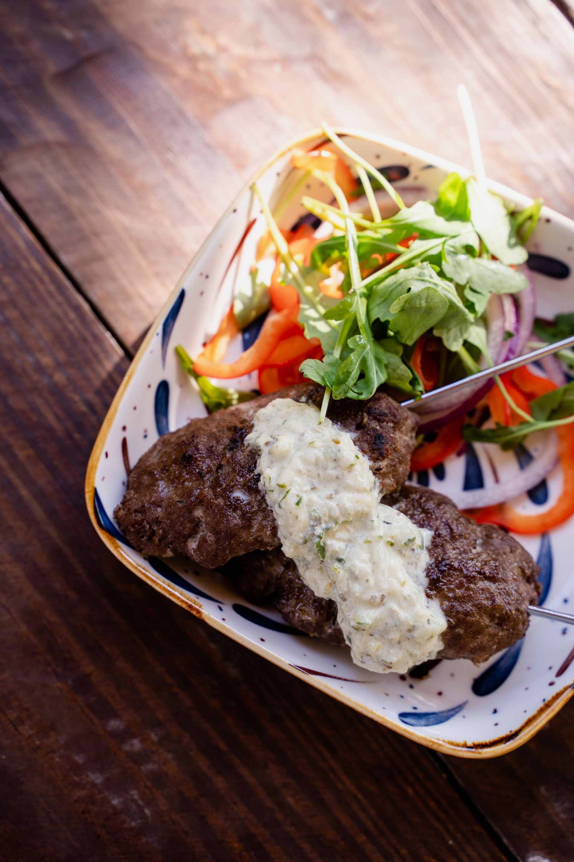 A plate of food with meat and vegetables on a wooden table.