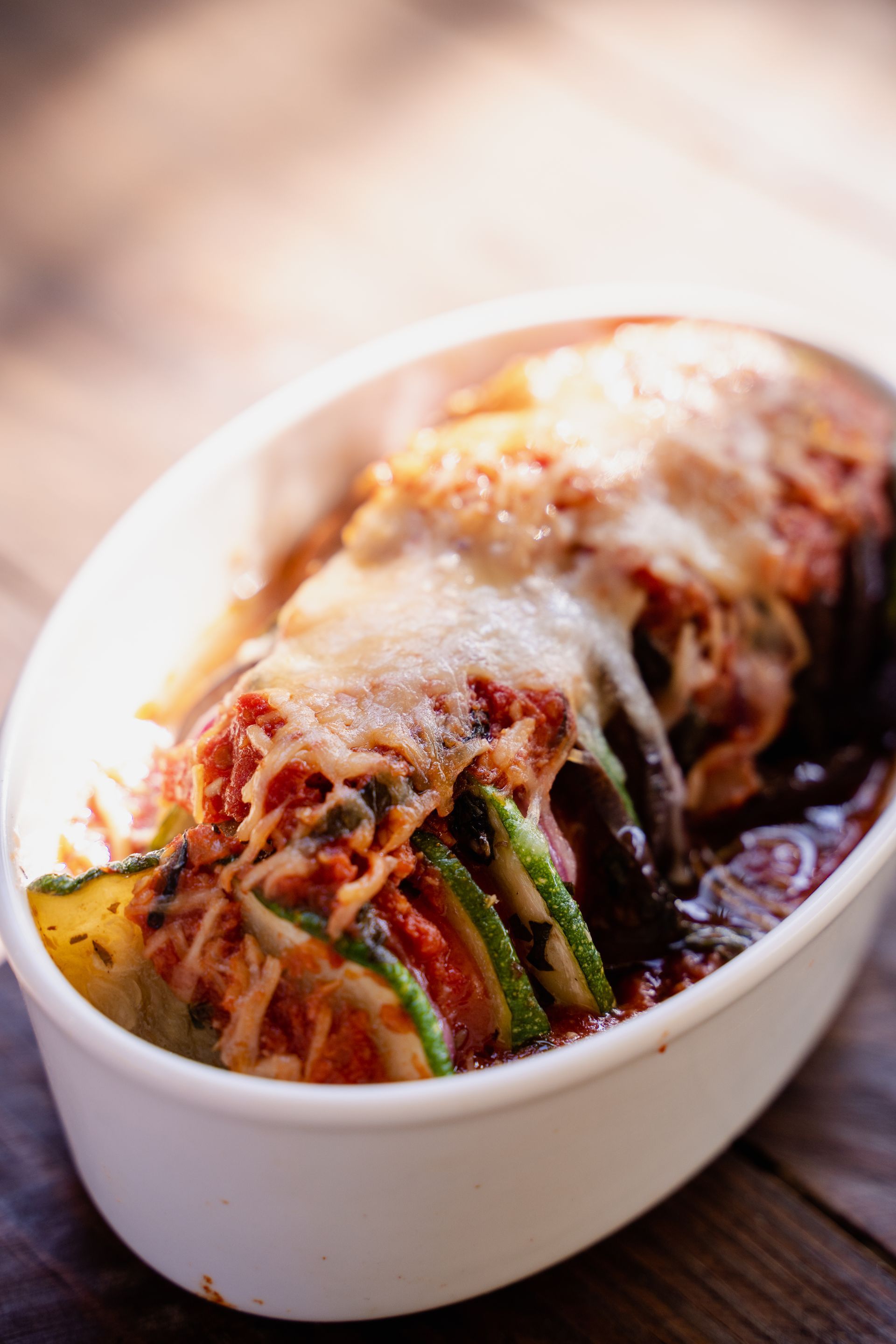 A casserole dish filled with vegetables and cheese on a wooden table.